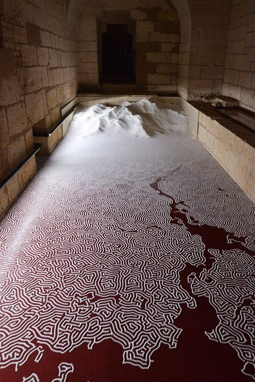 Intricate white salt maze on a red floor in a French castle.