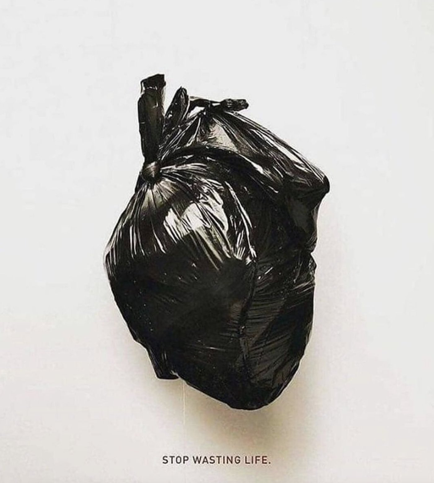 Image of a human heart wrapped in a black bin liner with the words Stop Wasting Life underneath