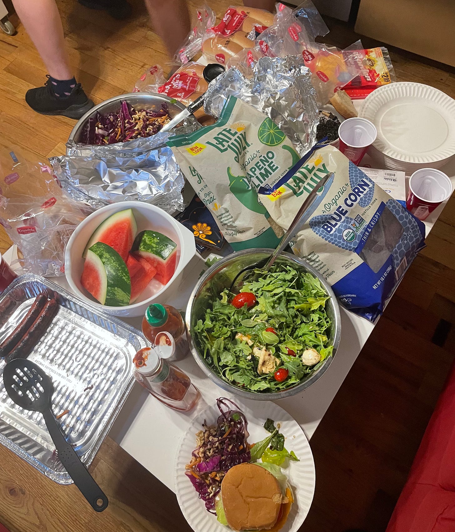 table of salad, fruit, chips, and other BBQ items