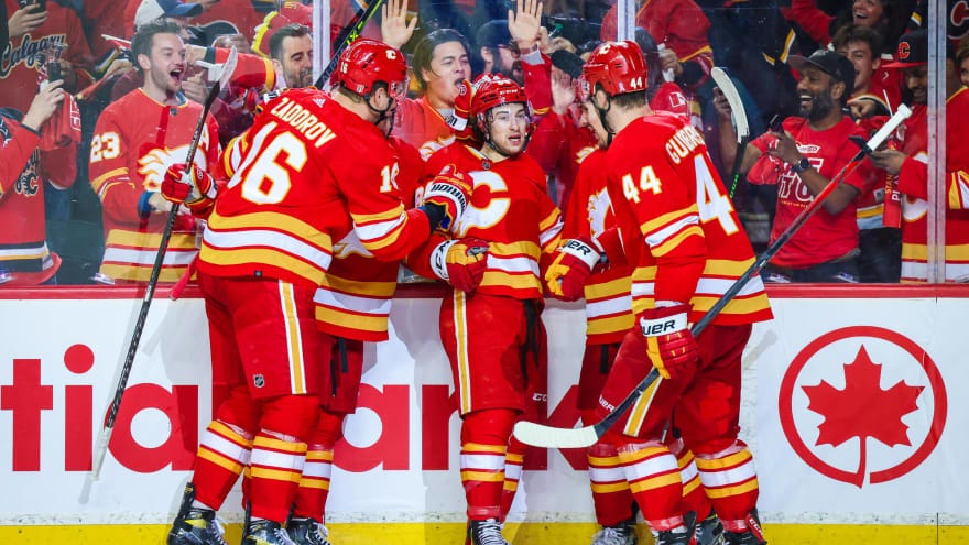 Picture of the Calgary flames players Zuadrov, and Johnny Gaudreau huddled up by fans.