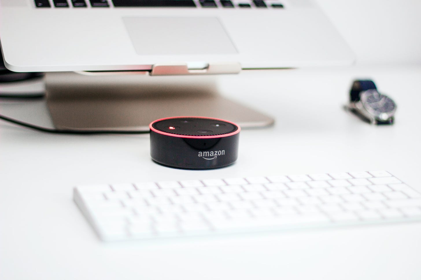 An Amazon Echo Dot showing a red ring in front of a laptop. Piotr Cichosz / Unsplash