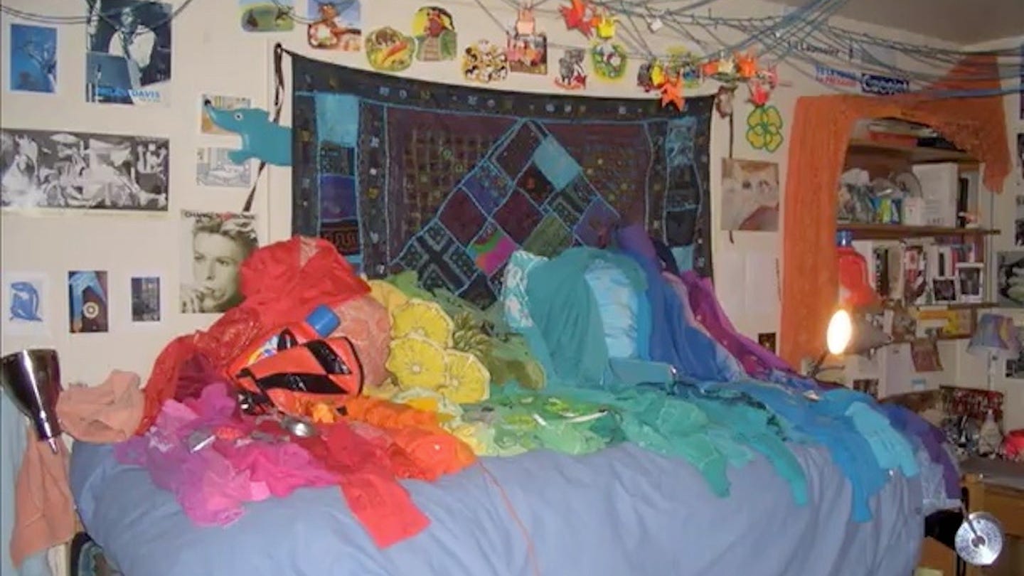 Clothes laid out in rainbow order on a bed, from 2006.