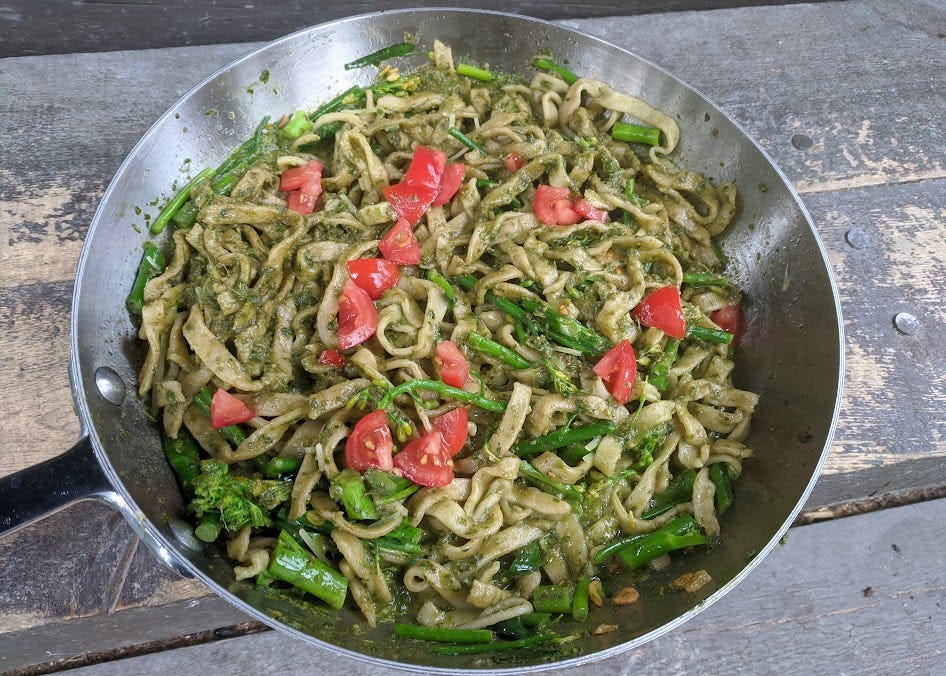 a pan of pasta with pesto, broccolini and fresh tomato