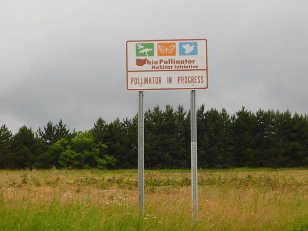 Image of road sign showing "pollination in process".