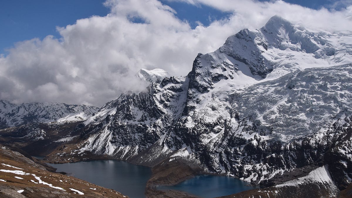 A glacier- and snow-covered high mountain peak with glacial lakes