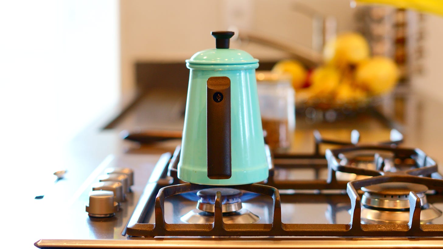 A teal kettle sitting on a lit gas stove