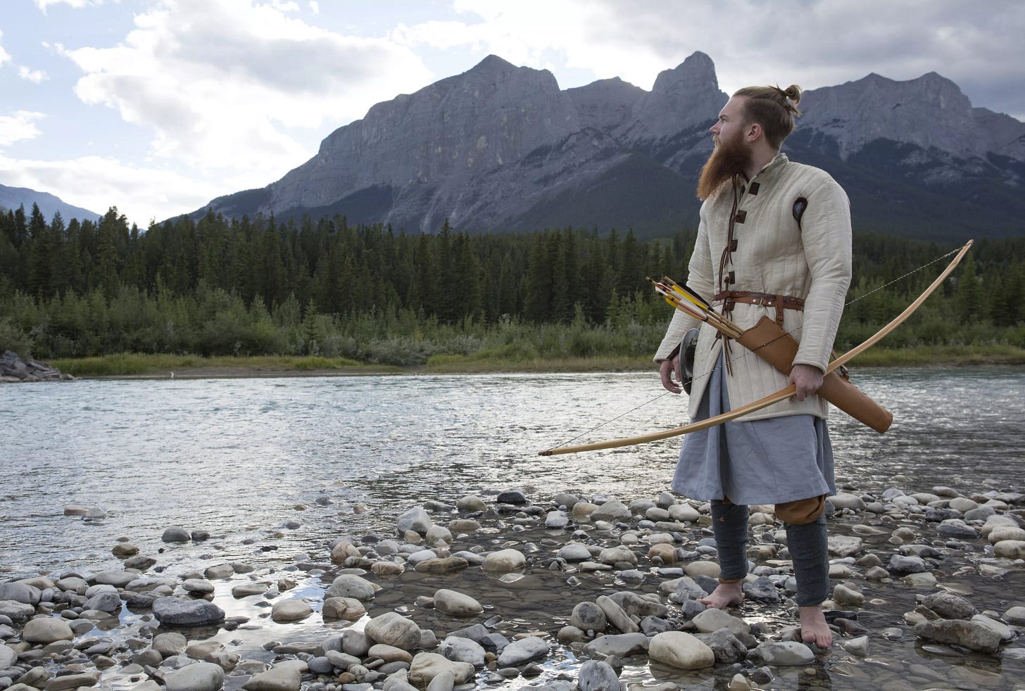 Man in viking warrior dress hunts by mtn river