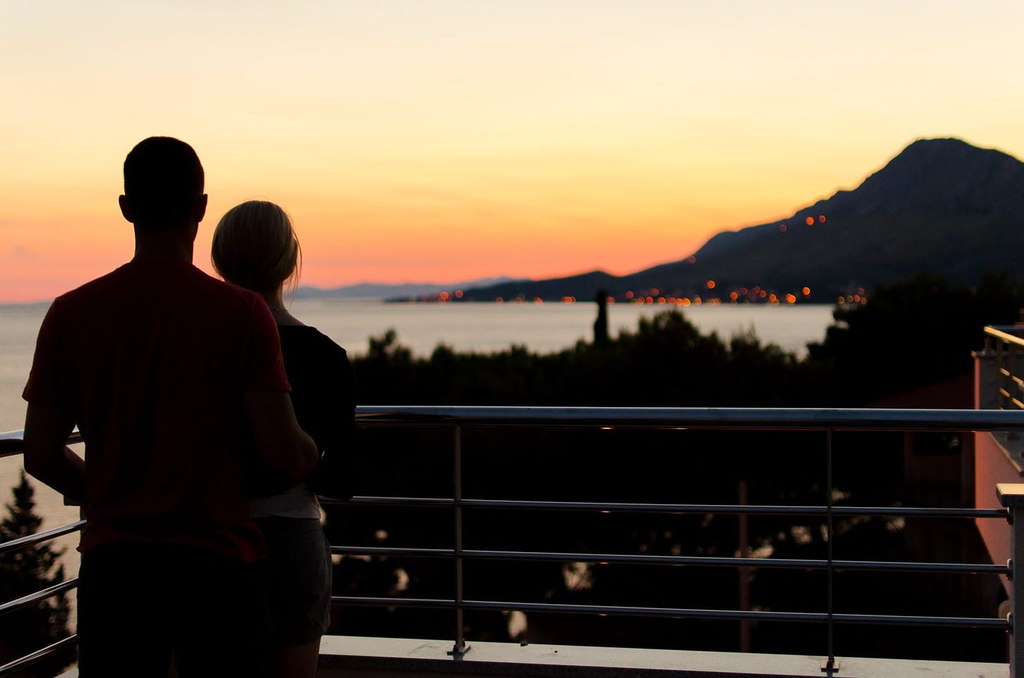 A couple on a balcony stare at the sunset