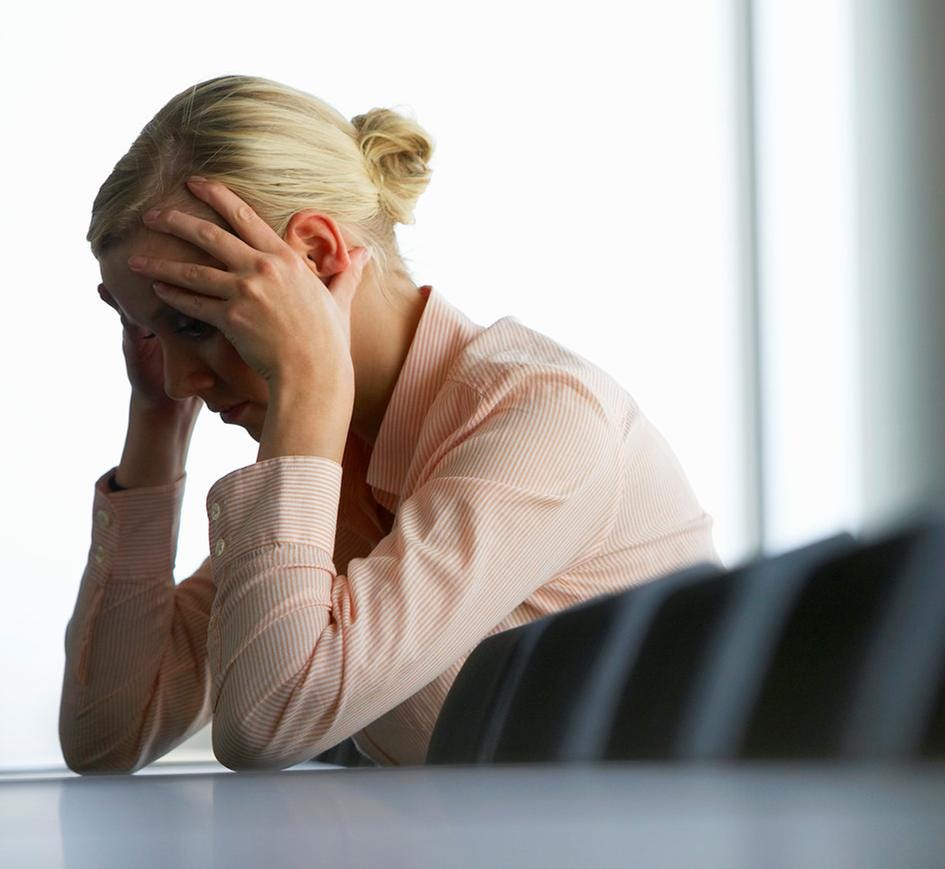 A picture of a woman in office attire, in despair