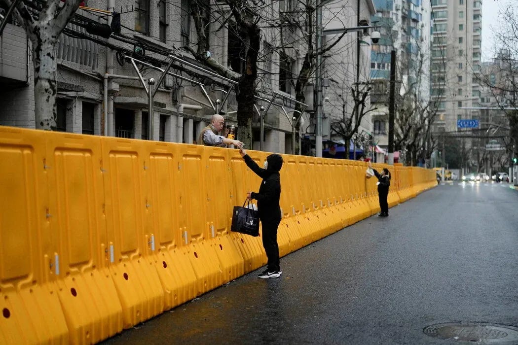 在上海一个采取封控管理小区，有民众隔墙取食 / Aly Song / Reuters