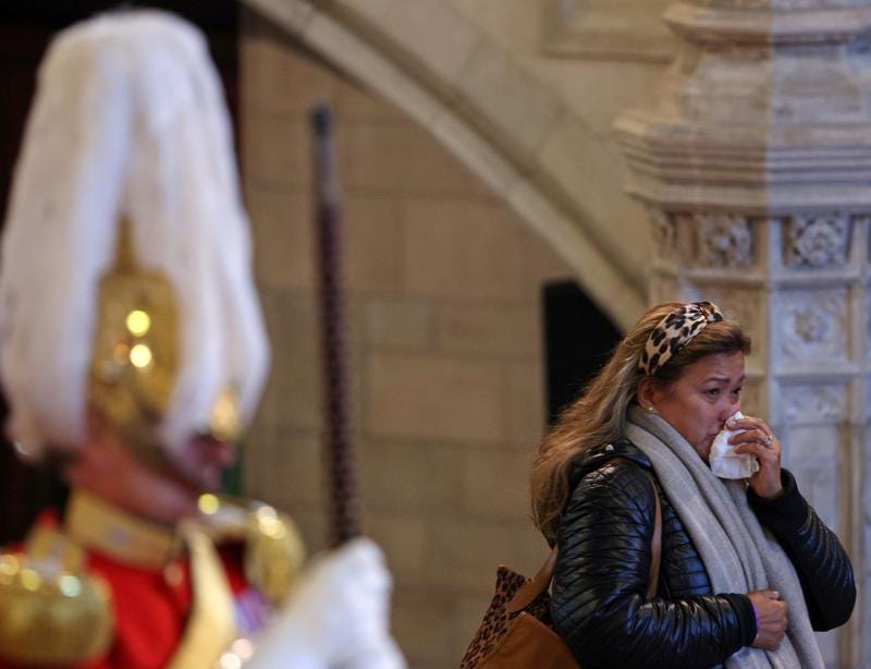 A woman wipes her nose as members of the public pay their respects as they pass the coffin of Queen Elizabeth II during its lying in State inside Westminster Hall, at the Palace of Westminster in London, Sunday, Sept. 18, 2022.  (Adrian Dennis/Pool Photos via AP)