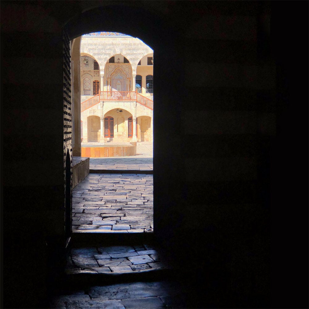 A dark passage leading into a wondrous-looking courtyard with a fountain and ornate doors