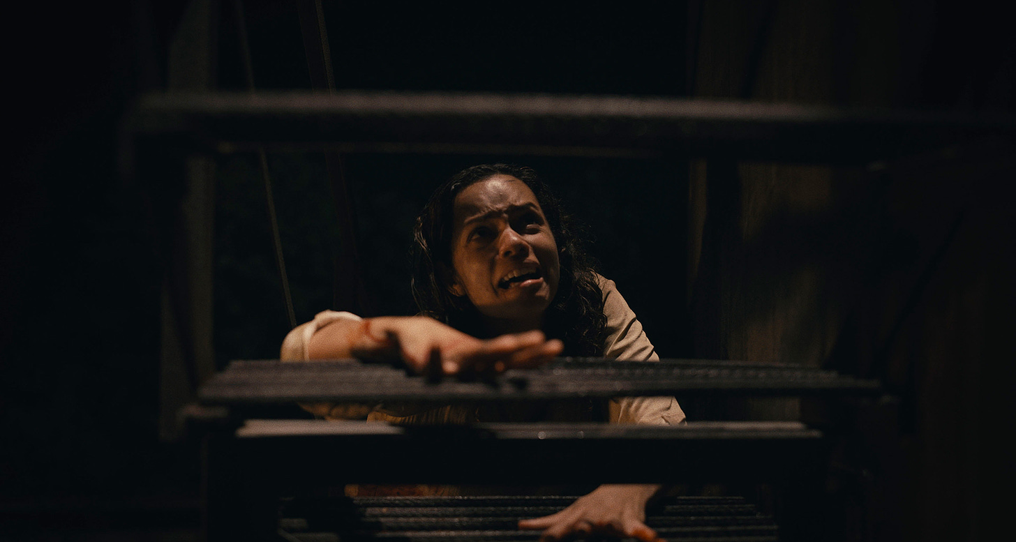 Film still for BARBARIAN with Georgina Campbell trying to climb up stairs.