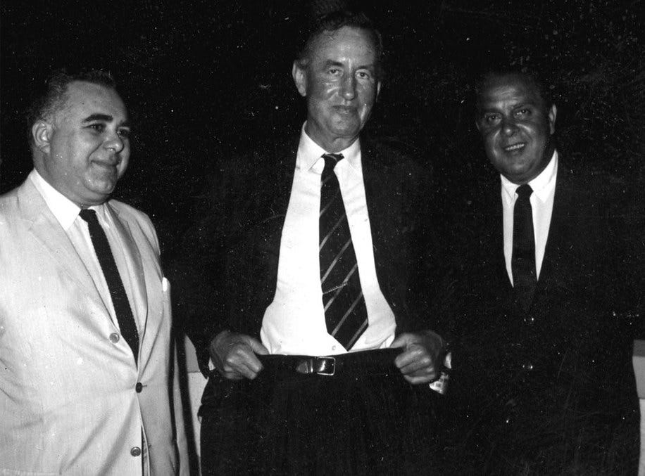 This black-and-white image shows the three men most responsible for launching the James Bond film franchise (from left to right): producer Harry Saltzman, Bond author & creator Ian Fleming, and producer Albert R. "Cubby" Broccoli. This black-and-white image shows the three men most responsible for launching the James Bond film franchise (from left to right): producer Harry Saltzman, Bond author & creator Ian Fleming, and producer Albert R. "Cubby" Broccoli.