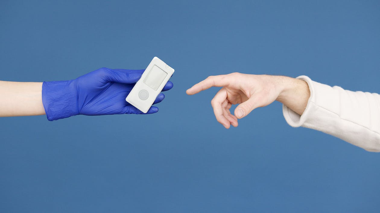 Free Person's Hand in Latex Gloves holding a Glucometer Stock Photo