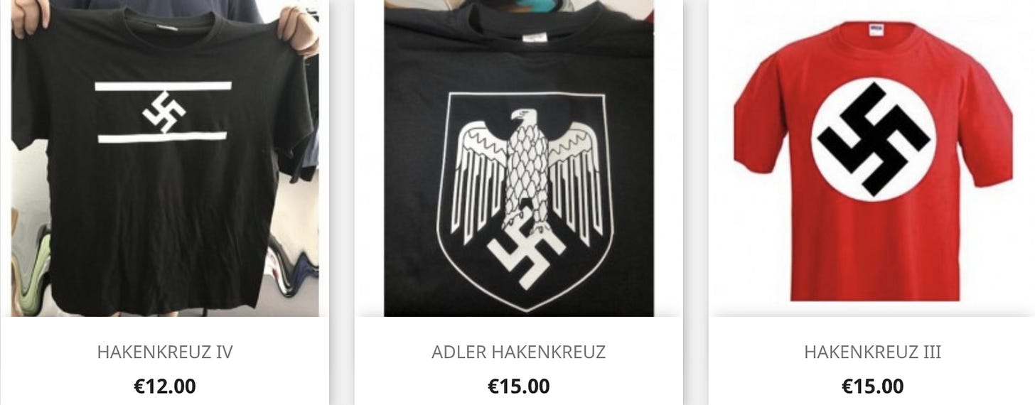 A row of three picture. The first on the left shows a black t-shirt with a hakenkreuz symbol in white on a black background with white stripes above and below the symbol. The middle picture shows another black t-shirt with a shield printed in white on the front showing a third reich eagle standing upon a hakenkreuz symbol. The picture on the right is a red t-shirt with a classic white circle and black hakenkreuz symbol in the center. All are labeled “HAKENKREUZ’ below them respectively.