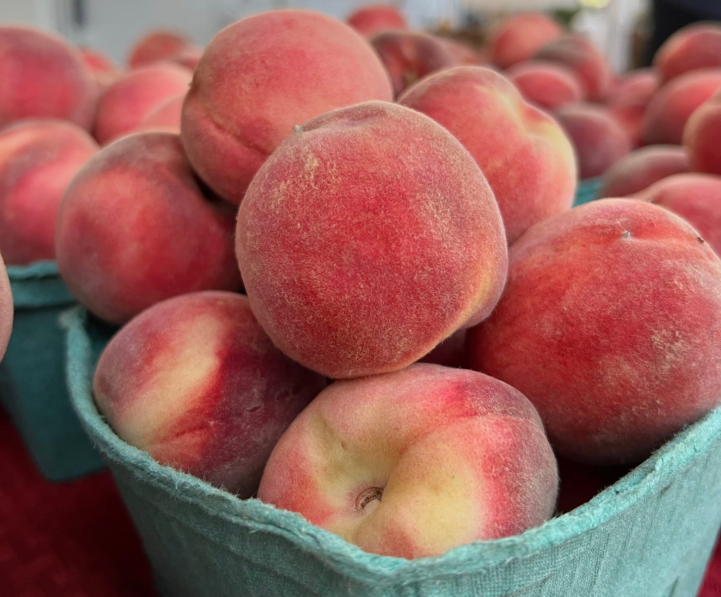 a basket of ripe peaches on a table at a farmers market