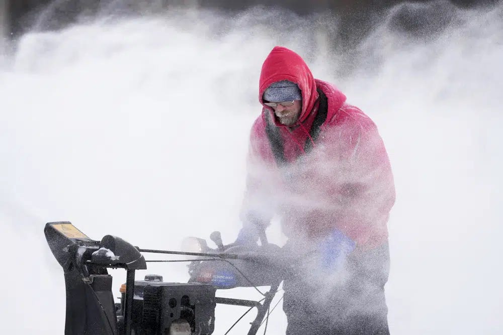Mark Sorter clears snow from a downtown ice skating rink, Friday, Dec. 23, 2022, in Des Moines, Iowa. (AP Photo/Charlie Neibergall)