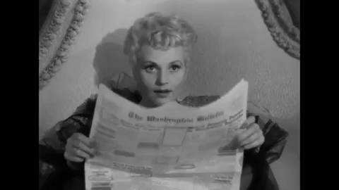 Judy Holiday in Born Yesterday with a newspaper smiling