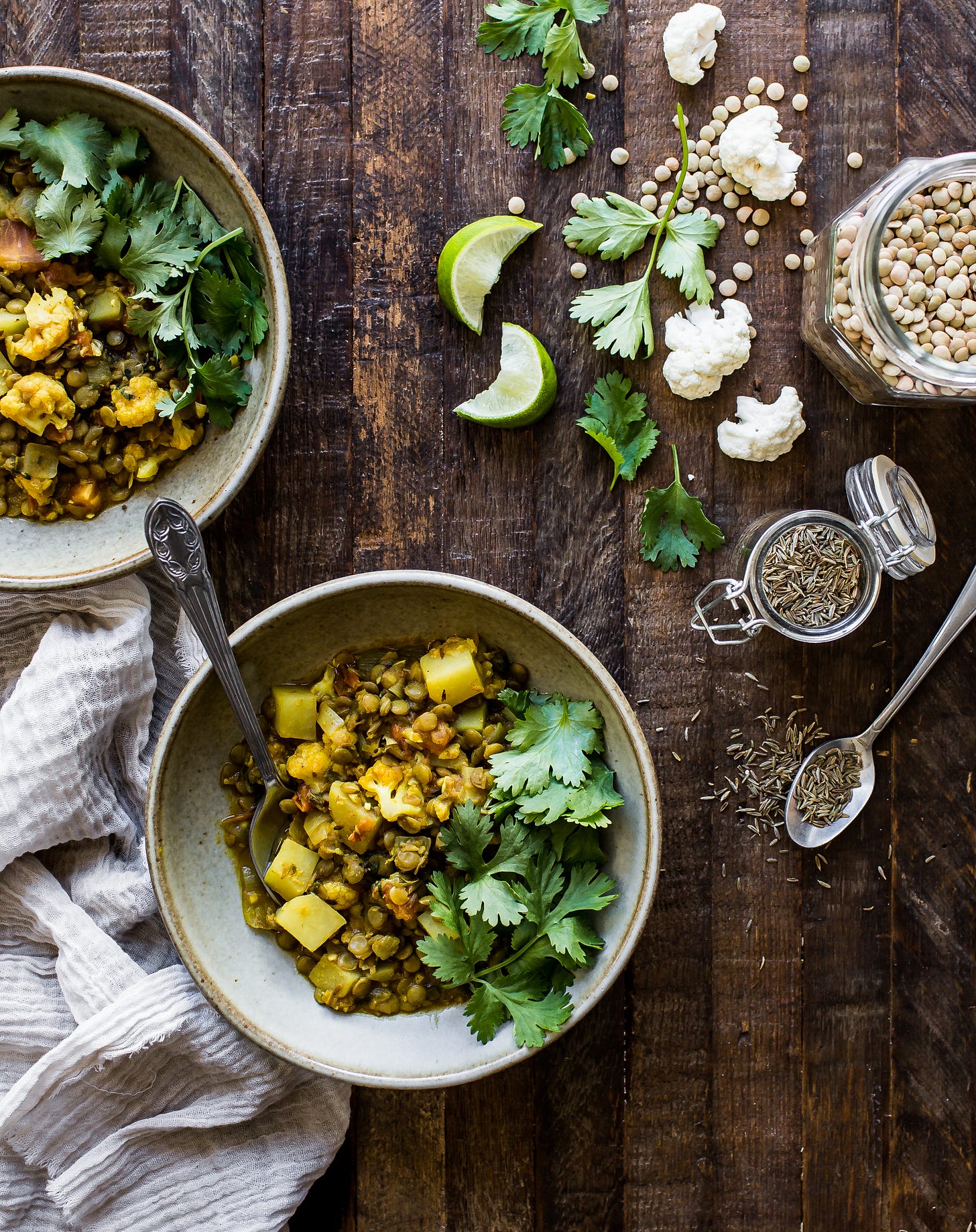 two bowls of cauliflower and potato dal, along with some of the ingredients