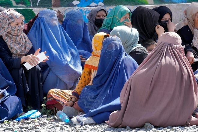 Afghan women wait to receive food rations distributed by a Saudi humanitarian aid group, in Kabul, Afghanistan, Monday, April 25, 2022. Afghanistan's  Taliban rulers on Saturday, May 7,  ordered all Afghan women to wear head-to-toe clothing in public, a sharp hard-line pivot that confirmed the worst fears of rights activists and was bound to further complicate Taliban dealings with an already distrustful international community.