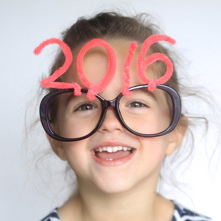 A close up of a girl wearing glasses that have pipe cleaner numbers on them for the New Year