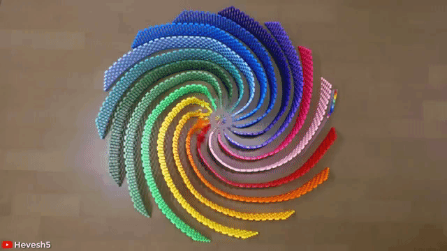GIF of dominoes falling in a rainbow spiral