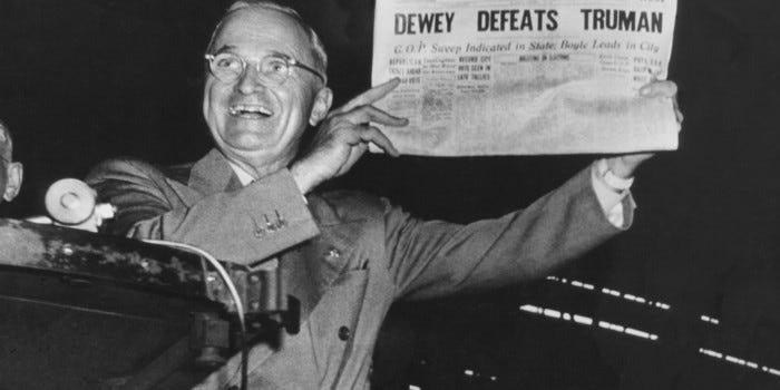 Picture of President Truman holding up a newspaper with the erroneous headline ‘Dewey Defeats Truman’. He looks happy.