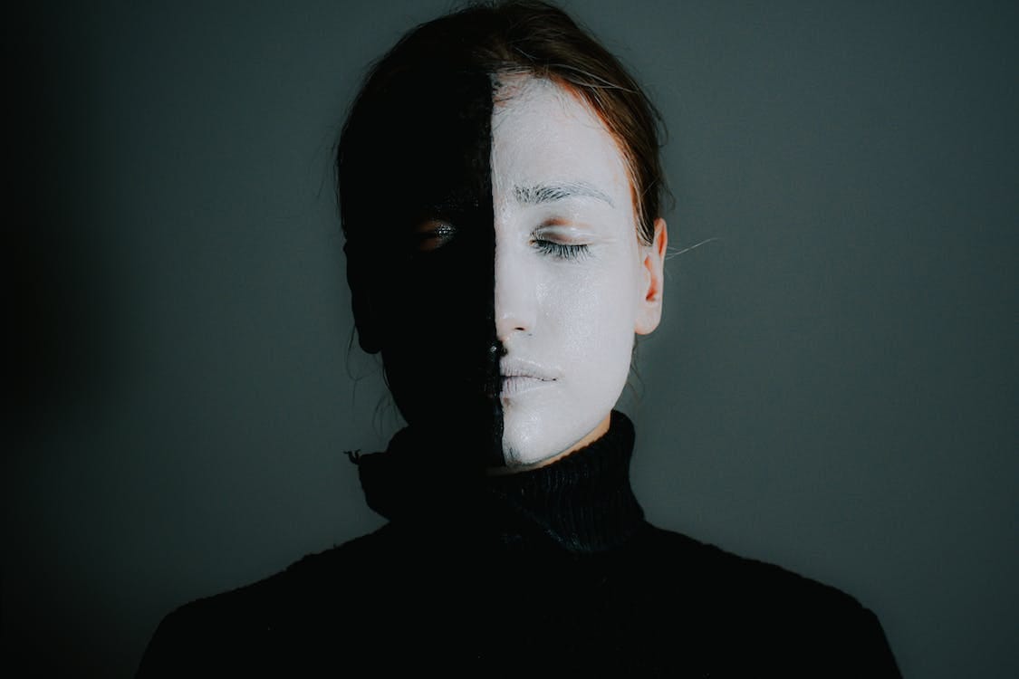Free Female with face painted in black and white standing with closed eyes Stock Photo