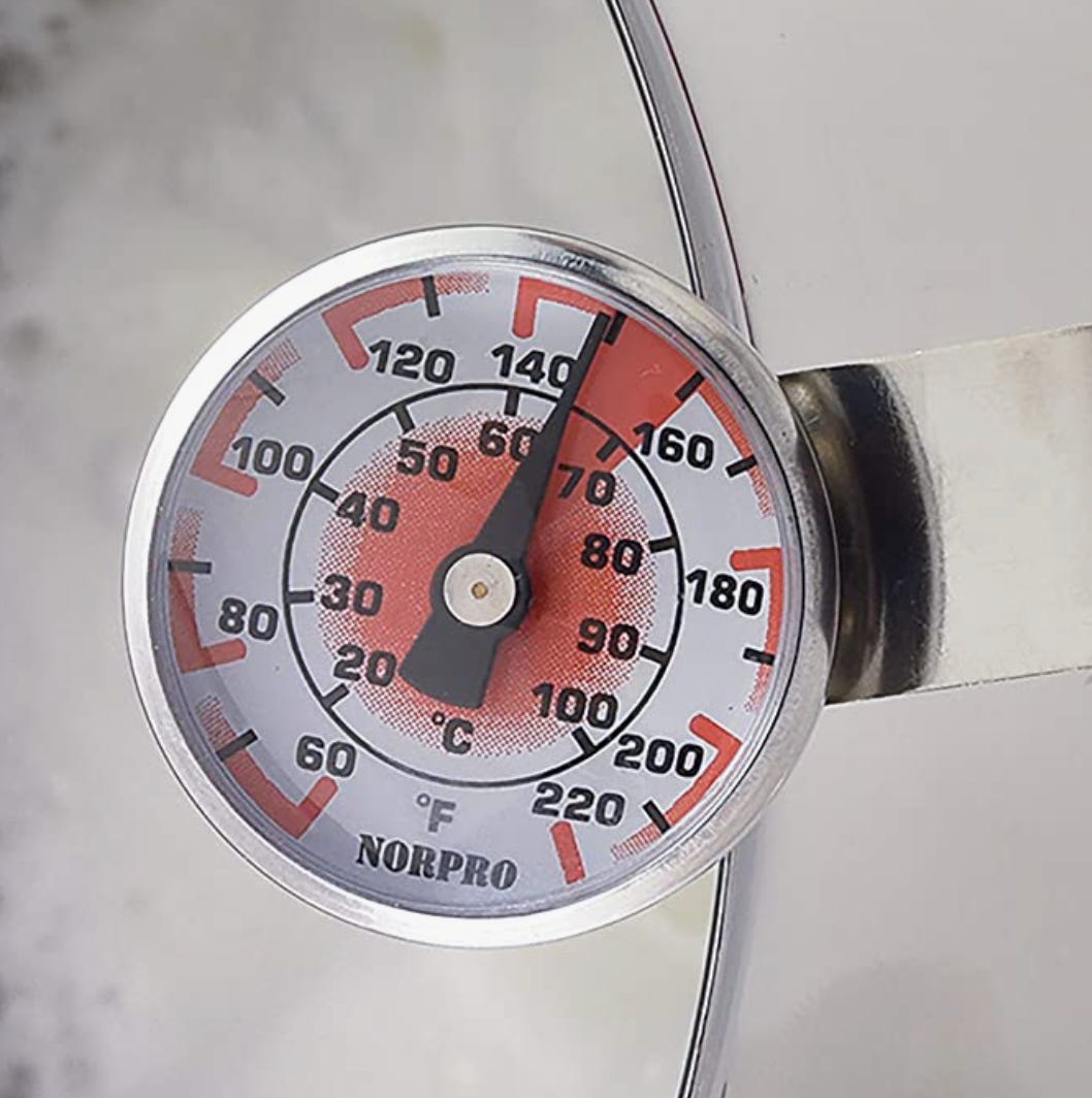 A close-up of a simple kitchen thermometer's numbered temperature gauge.