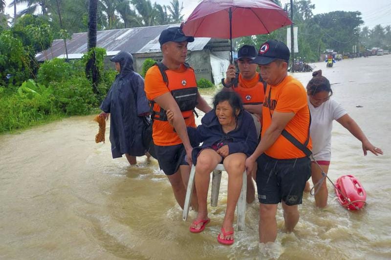 In this photo provided by the Philippine Coast Guard, rescuers evacuate residents from flood waters caused by Tropical Storm Nalgae in Hilongos, Leyte province, Philippines on Friday Oct. 28, 2022. Flash floods and landslides set off by torrential rains left dozens of people dead, including in a hard-hit southern Philippine province, where many villagers are feared missing and buried in a deluge of rainwater, mud, rocks and trees, officials said Saturday. (Philippine Coast Guard via AP)
