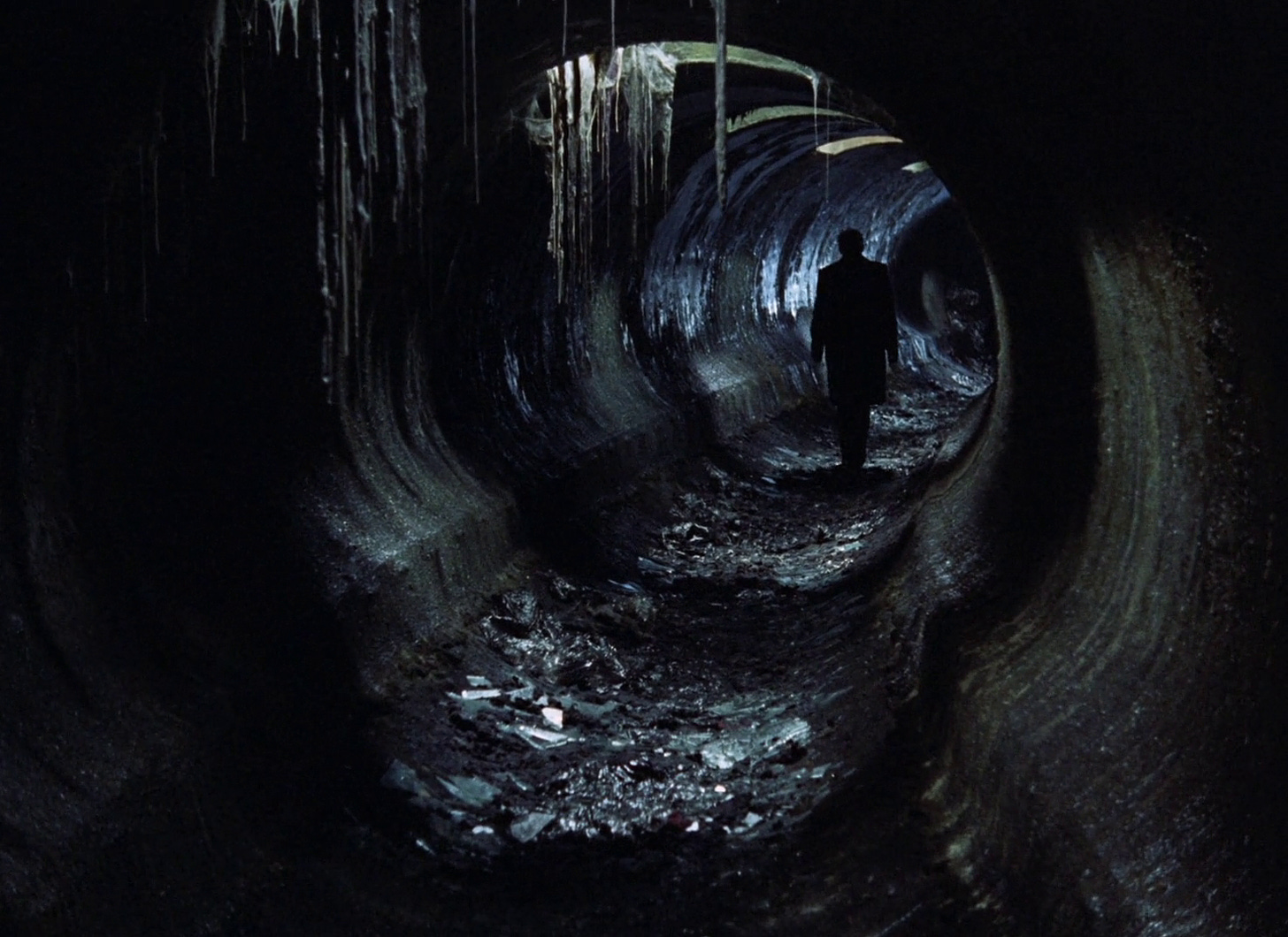 fotogramma tratto da Stalker, un film del 1979 di Andrei Tarkovsky, che ritrae un uomo dileguarsi giù per un umido tunnel