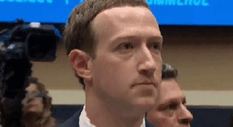 Zuckerberg, at a deposition, blinks and nods his head. He wears a suit and seems nervous.