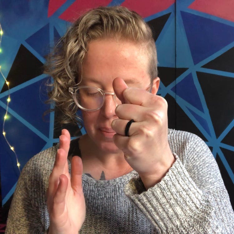 a person in front of a geometric background with one hand open and one in a fist, speaking