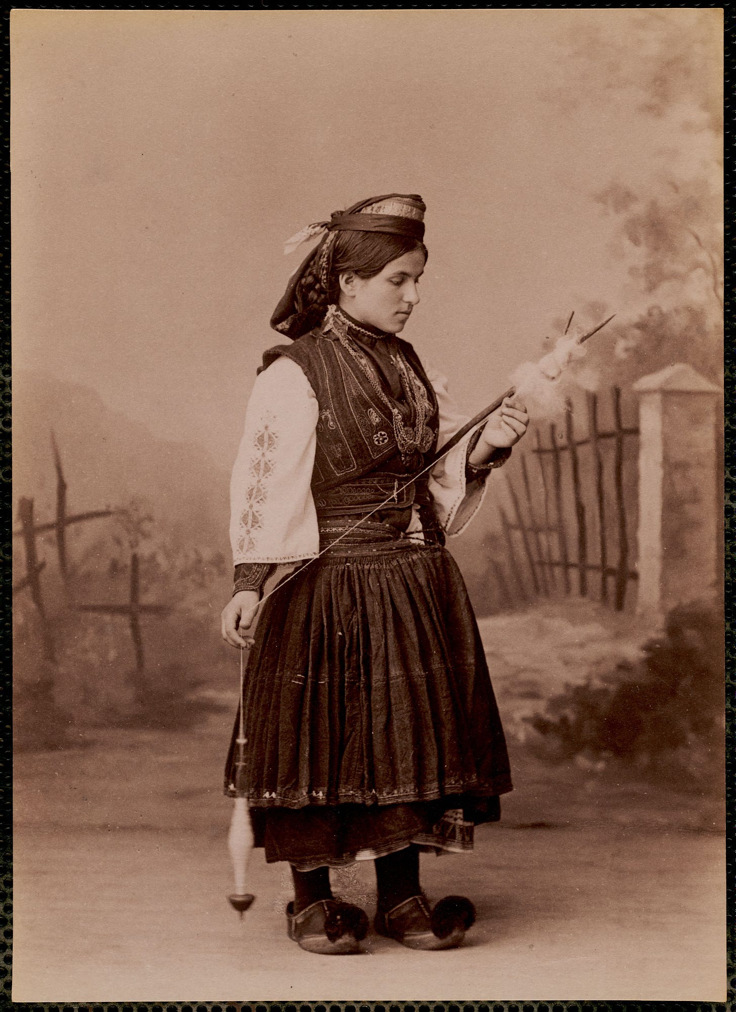 Studio_portrait_of_woman_in_traditional_Greek_dress_using_drop_spindle,_Kerkira_area,_Corfu,_c._1870-1900_-_commonwealth_js959312q.jpg
