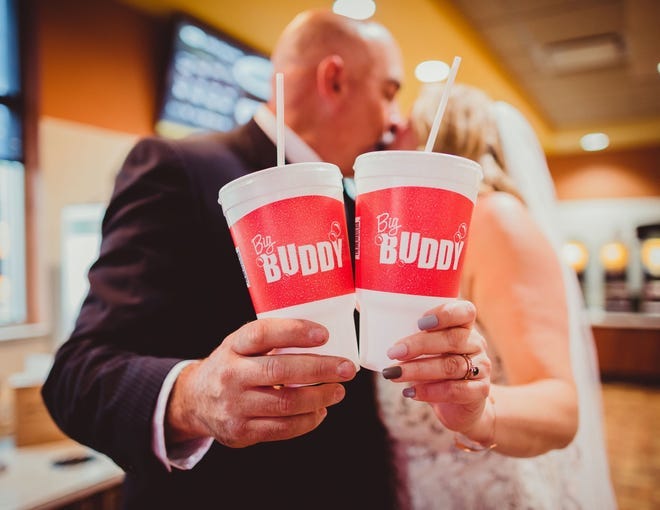 Mark Steinke and Ashley Ormes pose with Big Buddy cups during their wedding photo shoot at a Janesville Kwik Trip.