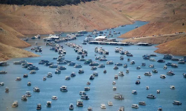 A photo of houseboats moored on Lake Oroville in 2021, showing the bare sides of the reservoir due to low water levels
