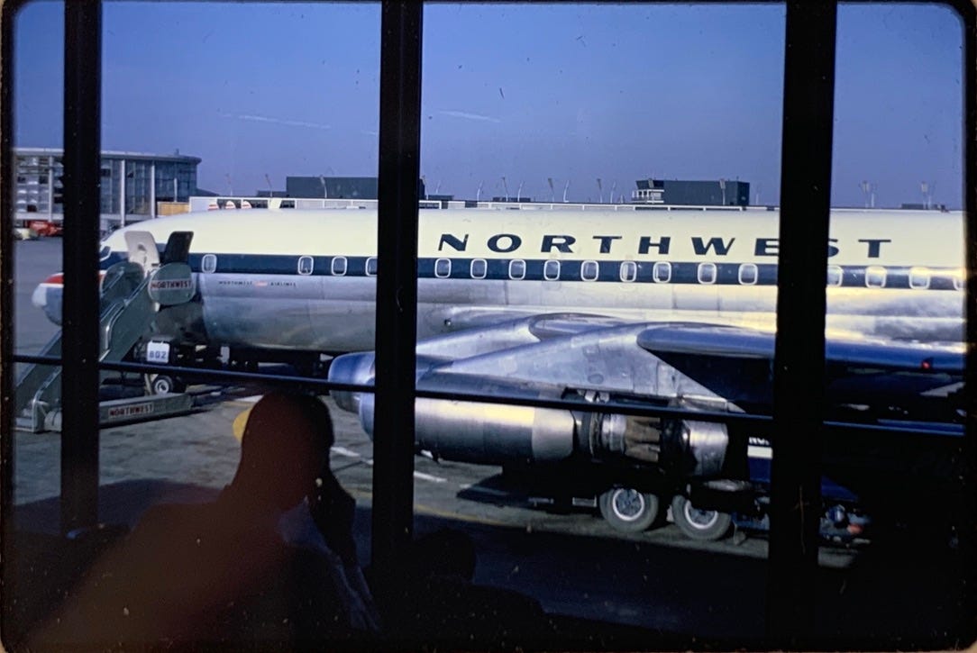 Photo of a white plane with blue text on the body reading "Northwest" from inside a window.