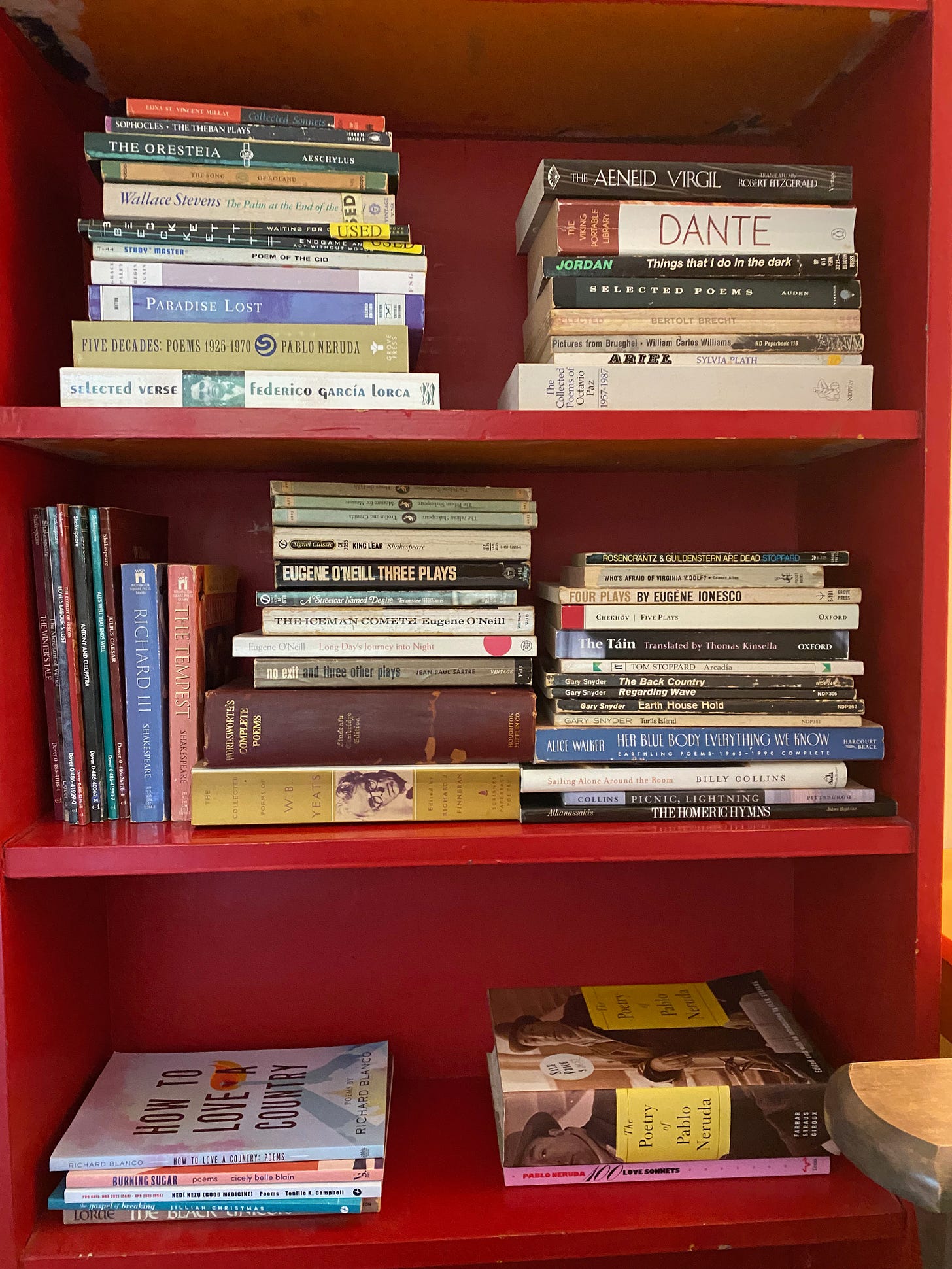 A red bookshelf full of stacks of books of varying shapes and sizes.
