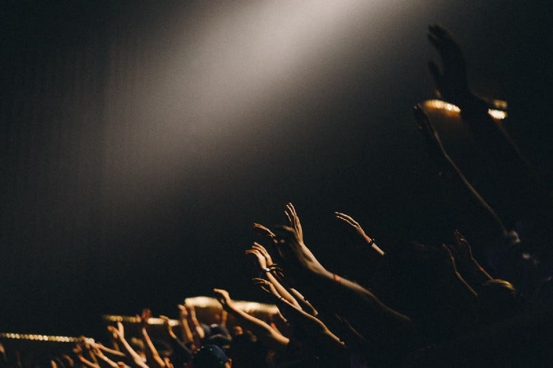 Raised hands and arms in a dark concert hall