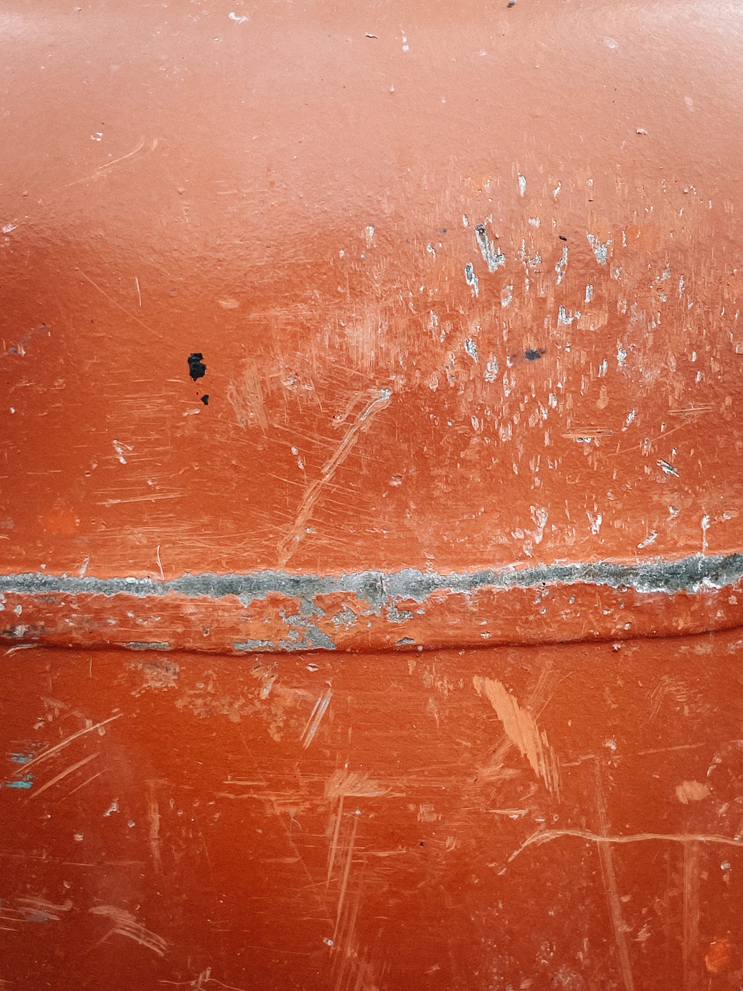 A close-up texture of a concrete mixer covered in scratches and dents.