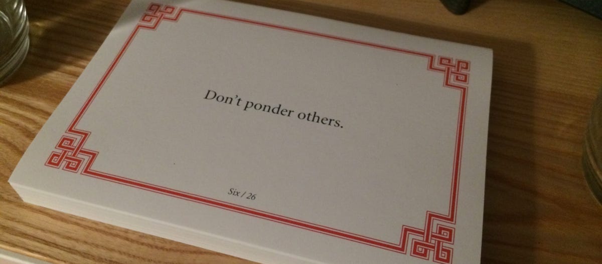 Lojong card on a wooden surface, which reads: Don’t ponder others.