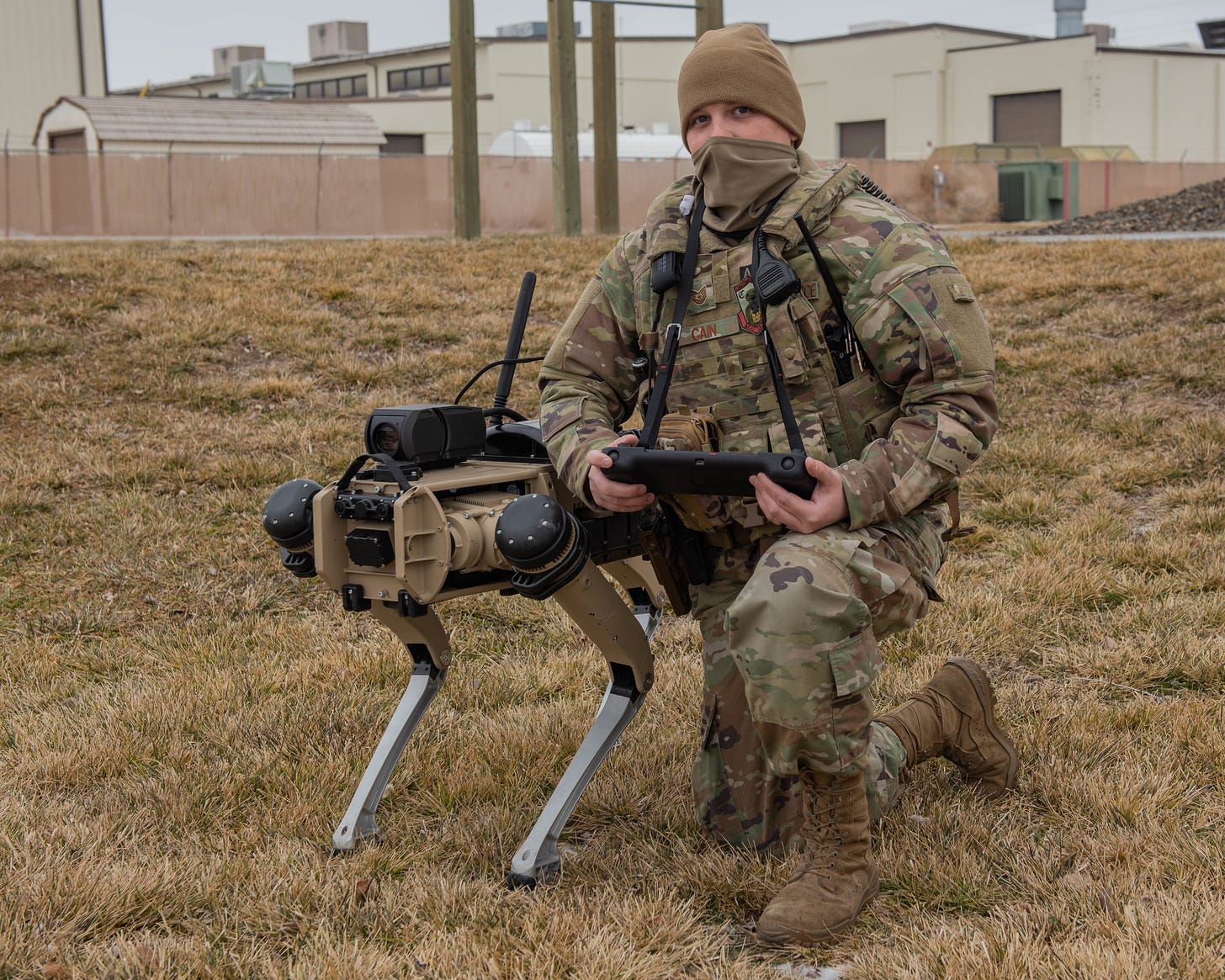 A human in inform poses next to a robot dog on a military base in Idaho.