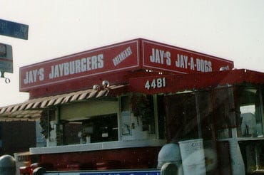 Old photo of Jay’s, a little grainy. You can see the top of the restaurant and it’s red sign with the restaurant name written in white. There is a red and white awning. 