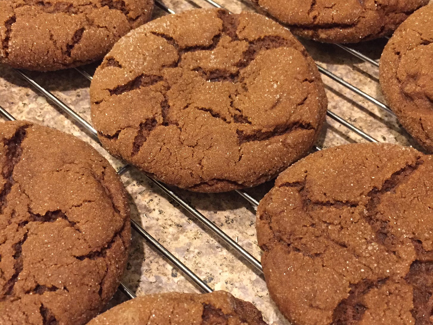 on a cooling rack, several ginger-molasses cookies with crackled, sugary tops. 