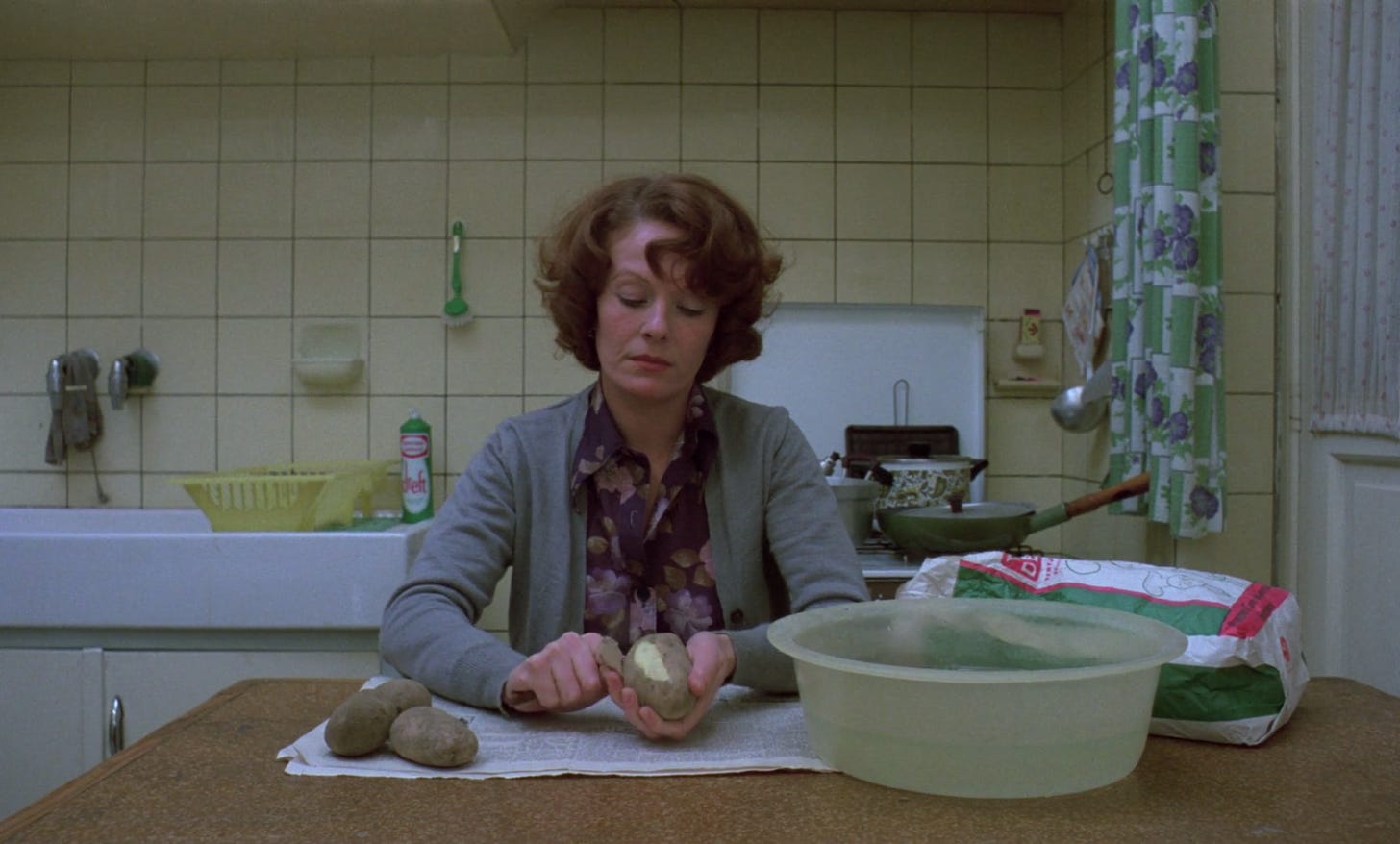 Jeanne Dielman sits centre-frame, sat at her kitchen table, peeling potatoes. Her slightly messed hair betrays her frazzled state at this, the halfway point of the film.