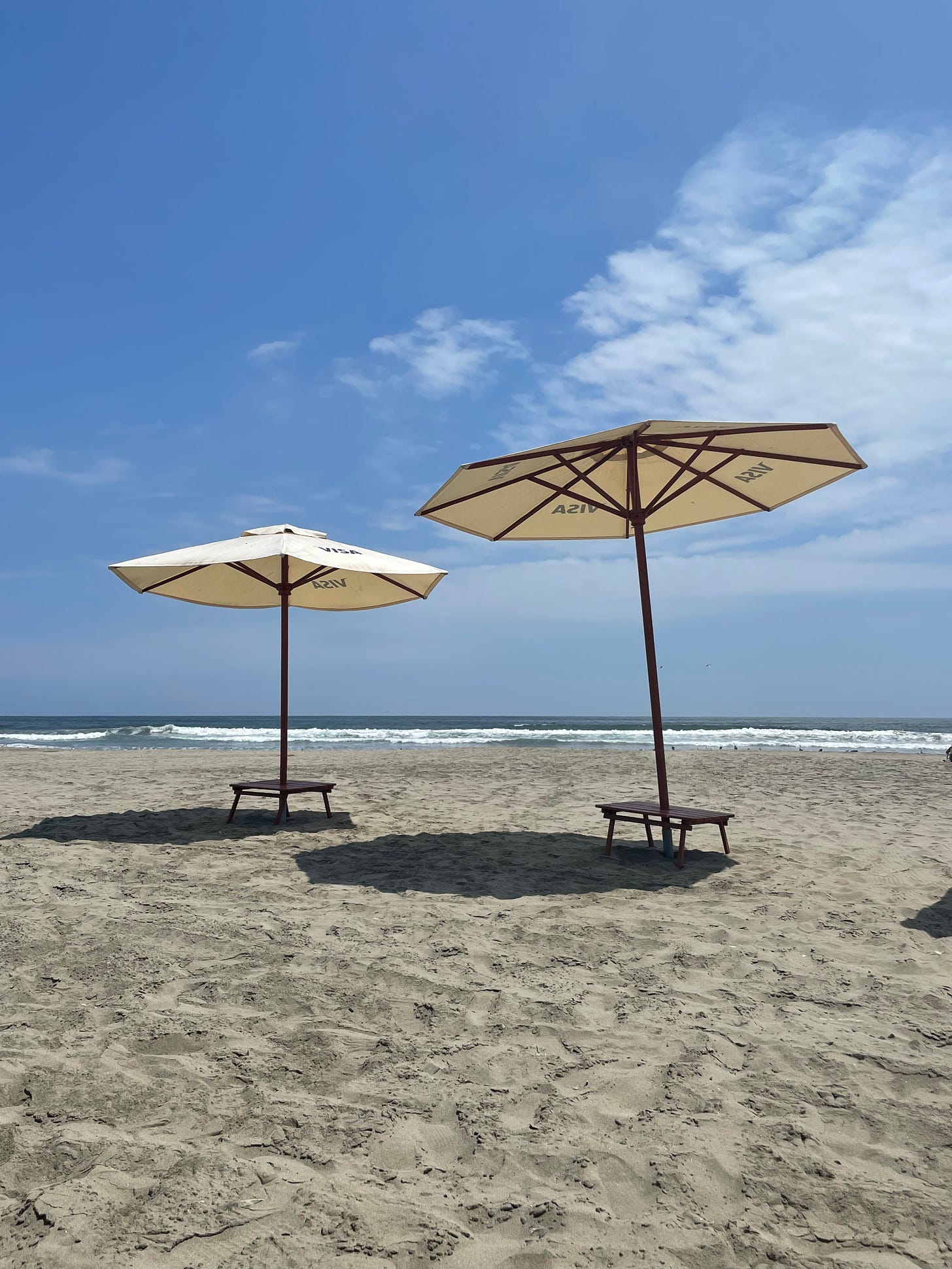 Two beach umbrellas on a sandy beach in Peru's coast