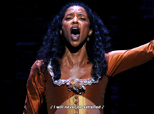 Gif de Angélica Schuyler em Hamilton com o braço extendido cantando "I will never be satisfied"