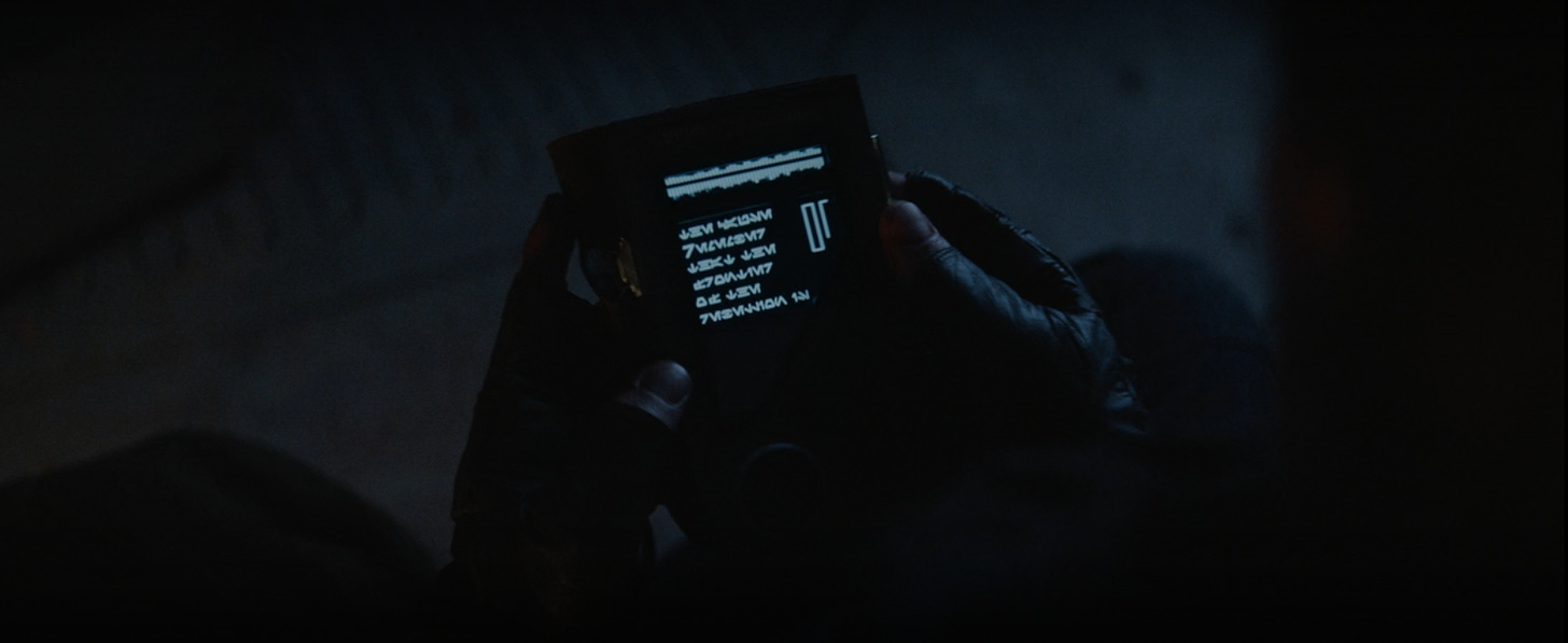 At night, a man holds a book, that displays a script in a Star Wars language.