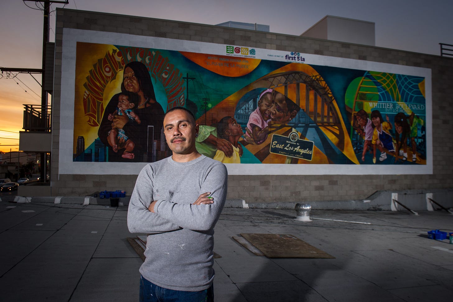 Artist Fabian Debora standing in front of his mural